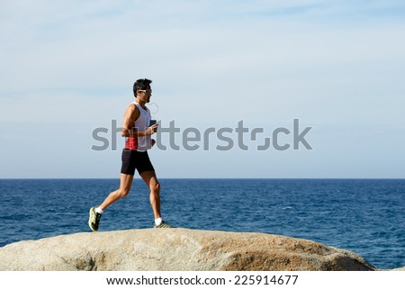 Middle age man at workout outdoors jogging along the sea at sunny day