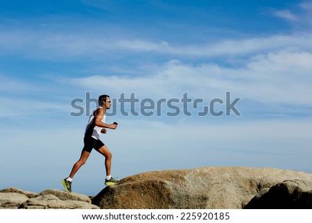 Healthy man in sportswear running fast over the rocks on sky background, healthy lifestyle and sport concept
