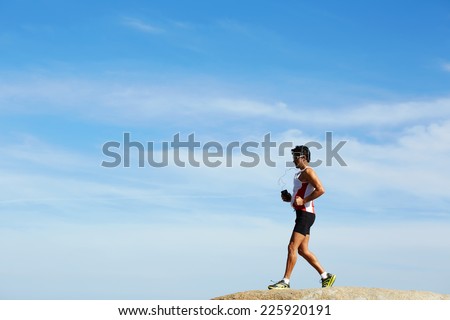 Male runner in sportswear running down over the rocks on sky background, healthy lifestyle and sport concept