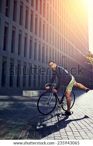 Stylish hipster man ready to ride on fixed gear bike, young handsome man standing with the bicycle in modern city zone, attractive young man ready to ride on fixed gear bicycle standing at sunset