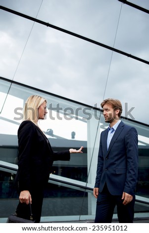 Boss and employee standing outside the office talking serious, confident businesswoman discussing with employee outside the office, business people standing near office building talking about the work