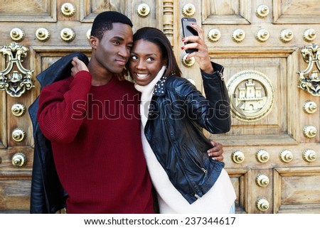 Best friends fooling around making self portrait with digital camera on phone, beautiful stylish couple taking a self portrait with smart phone, tourist man and woman making self portrait with phone