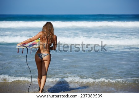 Teenager girl in swimsuit running fast to ocean waves holding her surfboard, hot surfer girl running to waves with her surfboard, beautiful young woman in bikini with surfboard run ready to surfing