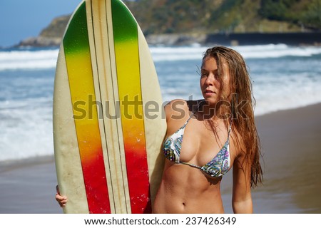 Attractive bikini model on summer vacation engage water sports, teenager girl in swimsuit holding her surfboard standing on seashore, recreation time on the beach at summer
