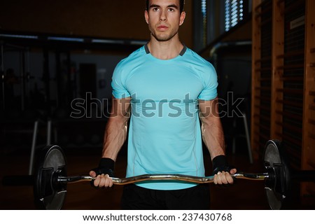 Muscular build man pumping up muscles with dumbbell, attractive young man training indoor, sportsman doing heavy dumbbell exercise for biceps, attractive young man training indoor