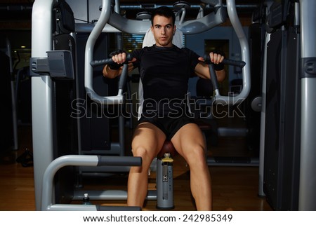 Handsome fit man flexing chest muscles working out at gym