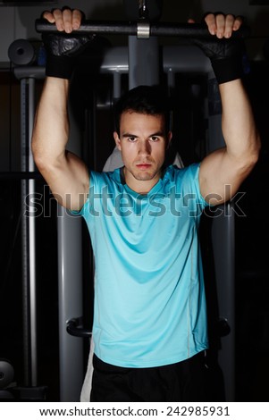 Young athletic man with muscular body doing pull up exercise in gym