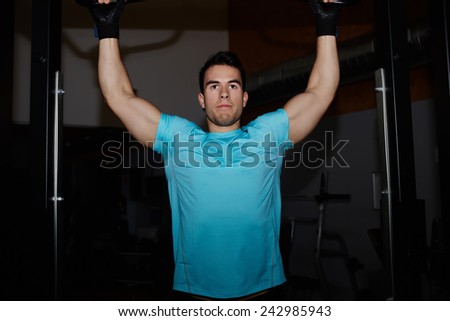 Young strong athlete doing pull up exercise at gym, professional bodybuilder training in fitness center