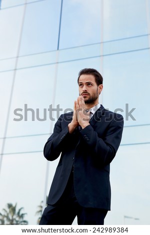 Half length shot of a worried business man standing near office building