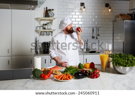 Portrait of happy male chef smell aroma of fresh tomato standing on big professional kitchen