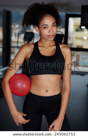 Portrait of pretty fit girl in sport clothes holding balance ball, young athletic woman having a rest after fitness training at gym