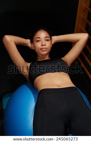 Young afro american woman exercising her abs lying on a balance ball