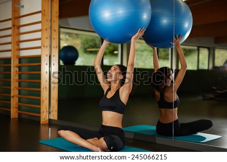 Charming afro american girl holding up balance ball and enjoying time at gym, young fit woman looking so happy