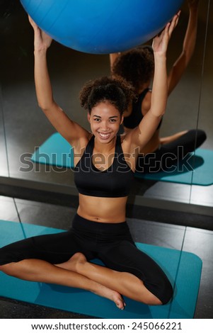Portrait of charming afro american girl holding up balance ball and enjoying time at gym
