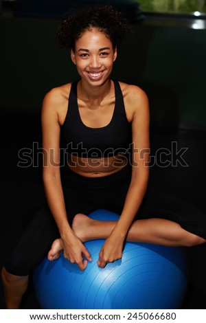 Attractive fit woman in sport clothes sitting on balance ball and looking to the camera