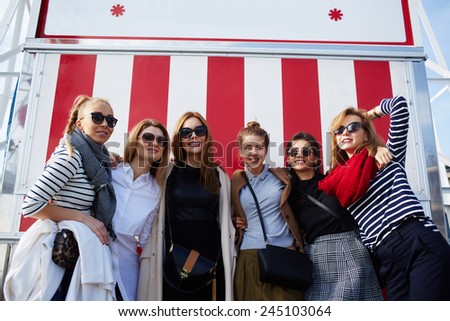 Outdoor portrait of beautiful group of women having fun and smiling against fair decoration