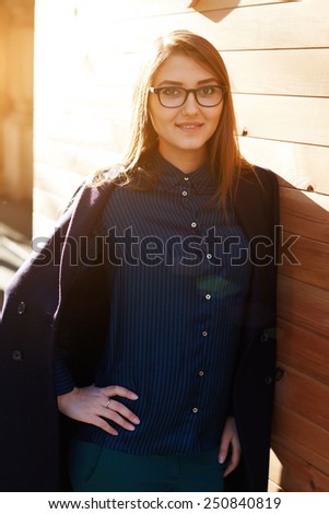 Portrait of cute smiling girl looking at you standing outdoors at sunny evening