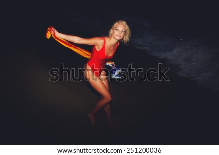Hot sexy model posing on the ocean beach at night holding Catalonia flag, blond hair girl in red swimsuit posing on the beach, picture specially made with vintage and noise effect