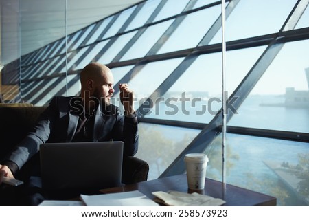 Side shot of handsome successful businessman pensively gazing out of the window thinking about the work plan, attractive young business man looking out of airport hall window, deep in thought
