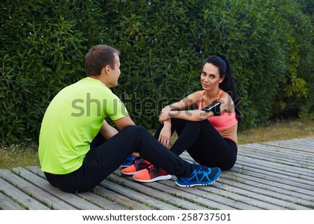 Beautiful sport couple resting after workout sitting in beautiful park, couple in love training together, couple of runners enjoying to each other while they having a rest after workout
