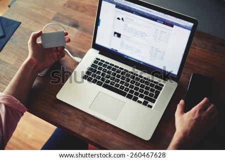 Cropped shot of a man\'s hands using a laptop at home while holding credit card, data security, on-line shopping at home, cross process, filtered image, focused on the left hand with gift card