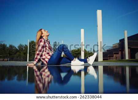 Side view shot of a young woman sitting in the park and enjoying the sunshine feeling so happy,relaxing girl enjoy outdoors with closed eyes, girl sitting next to the water with reflection of her self