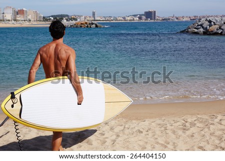 Rear view attractive man with sexy body going to the sea holding big copy space surfing board, handsome man walking on shoreline at beautiful sunny day, professional surf rider began his surf session