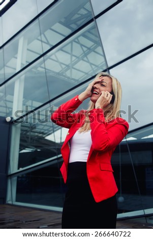Portrait of attractive businesswoman throwing her head back with one hand on her face in laughter having conversation on cell phone, woman laughing during talking to friend on smart phone, filter