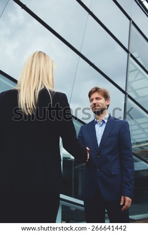 Rear view managing businesswoman shaking hand with smiling employee outside the office, business handshake and trust concept, business colleagues having agreement in conversation or discussion