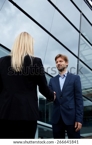 Rear view managing businesswoman shaking hand with smiling employee outside the office, business handshake and trust concept, business colleagues having agreement in conversation or discussion