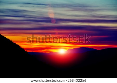 Amazing view with colorful sunset and sun rays over mountain landscape