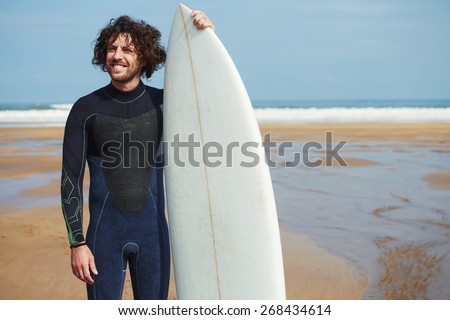 Smiling surfer man with long hair holding surf board with copy space for advertising, surfer standing on the beach with beautiful ocean horizon on background, cross process image, flare light