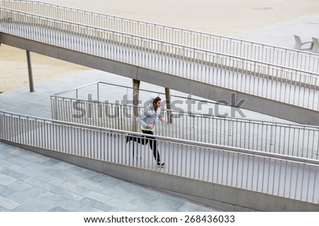 Full length shot of athletic male jogger running fast over little bridge at early morning