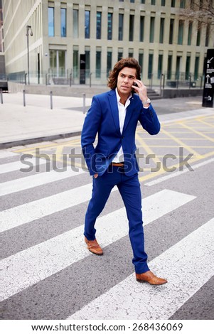 Full length portrait of a handsome young man making a call on his mobile phone while walking in big city, handsome businessman in a suit talking on his smart phone