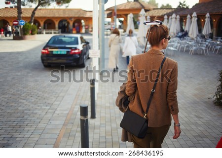 Rear view of stylish young woman holding stick with smart phone walking in new city, technology and travel