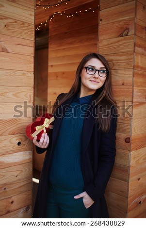 Portrait of elegant woman with glasses standing outdoors with beautiful Valentine\'s gift presented by her boyfriend, Valentine\'s Day celebration