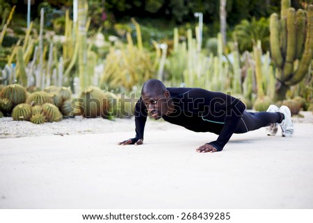 Fit dark skinned man in active clothes doing push-ups exercise outdoors, sporty black man training outside
