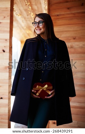 Portrait of elegant young woman holding red heart gift box presented by her boyfriend on Valentine\'s Day