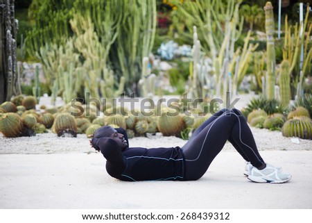 Fit man doing sit ups exercise before going for a run outdoors, sporty black man training outside