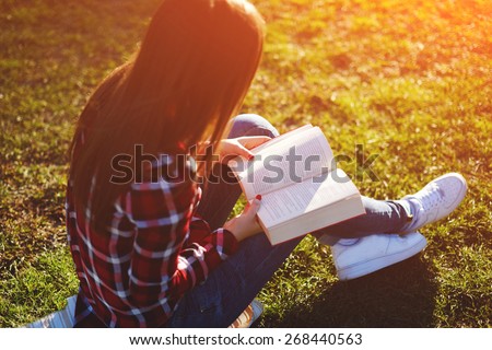 A young lovely woman relax reading an absorbing novel in beautiful the park