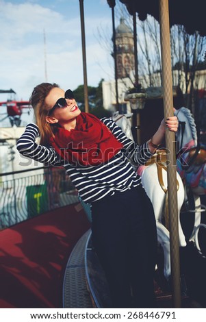Portrait of stylish hipster girl having fun at recreation time in amusement park, attractive young woman enjoying sunny afternoon while resting in fun fair park, filtered image