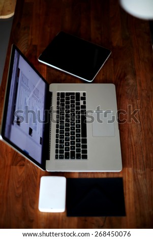 Top view shot with laptop computer and digital tablet on wooden desk, hard drive and black envelope, mock up presentation with workplace focus on keyboards