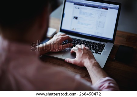 Cropped shot of a man's hands using a laptop at home, rear view of business man hands busy using laptop at office desk, young male student typing on computer sitting at wooden table