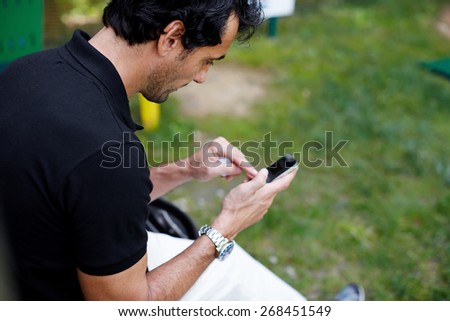 Side view of brunette hair mature man typing message on mobile phone, people using technology everywhere, man typing text on smart phone outdoors, focus on the face