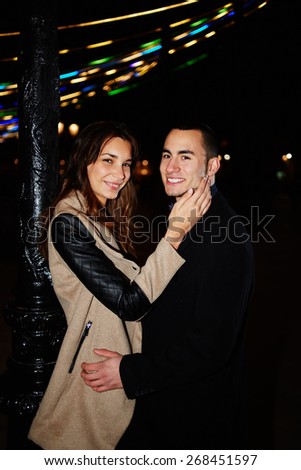 Portrait of romantic happy couple at night walk on Valentine\'s Day outdoors, beautiful young couple standing outside with night lights on background