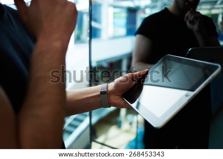 Side view male person using digital tablet, business man or freelancer working on touch pad in elevator, businessman executive using wireless devices in modern office, young successful browsing on pad