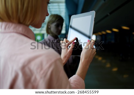 Rear view female person using digital tablet, business woman or freelancer working on touch pad in elevator, businesswoman using her wireless devices in modern office, young successful browsing on pad