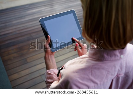 Close up young female student using blank screen touch pad against wooden background, freelancer girl working on digital tablet with copy space, hipster woman browsing with touchscreen device, filter