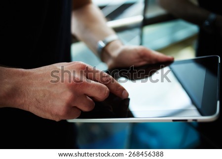 Cropped shot of male person using a digital tablet, man\'s hand typing text message zooming digital image on touch pad, businessman using his wireless devices during a meeting, work on a tablet screen