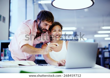 Young asian businesswoman getting advice from office colleague at her desk, couple of businesspeople deep in discussion before a laptop in a corporate lounge, students talking together over computer